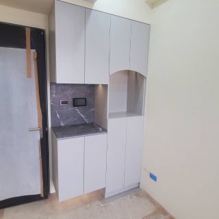 富霖映樂玄關收納規劃：灰色門片鞋櫃結合石紋檯面與圓弧展示區，營造質感進門端景。