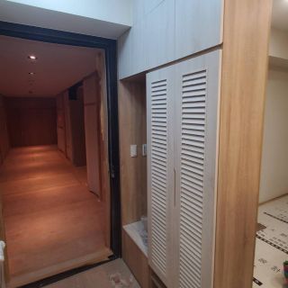 西屯匯熊小姐室內設計案例：客製化木紋玄關系統櫃，採用通風百葉門片設計與整合式收納座榻，優化門口坪效並營造現代簡約氛圍。