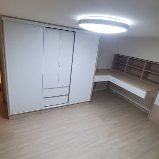 苗栗室內裝修實景：一體化書桌櫃與三門滑軌衣櫃設計，營造一致性的淺木紋居家空間。