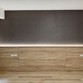 惠宇敦品床頭背板工法：木紋面板內嵌整合式插座配置，搭配上方灰色質感背牆與間接燈光。