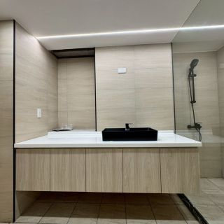 惠宇敦品衛浴設計細節：黑色質感 vessel sink 臉盆、木紋懸空浴櫃與牆面間接照明美學。