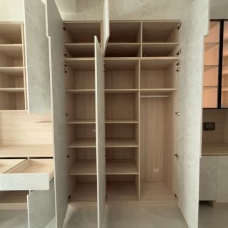 嘉義簡小姐臥室衣櫃規劃：頂天立地石紋系統衣櫃開啟實景，展示大容量掛衣區與儲物空間。